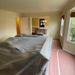 Furniture moved to the center of the room and wrapped in plastic, with rosin paper taped down over the floor before interior painting starts