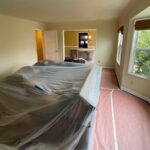 Furniture wrapped in plastic and red rosin paper protecting the floor before interior painting
