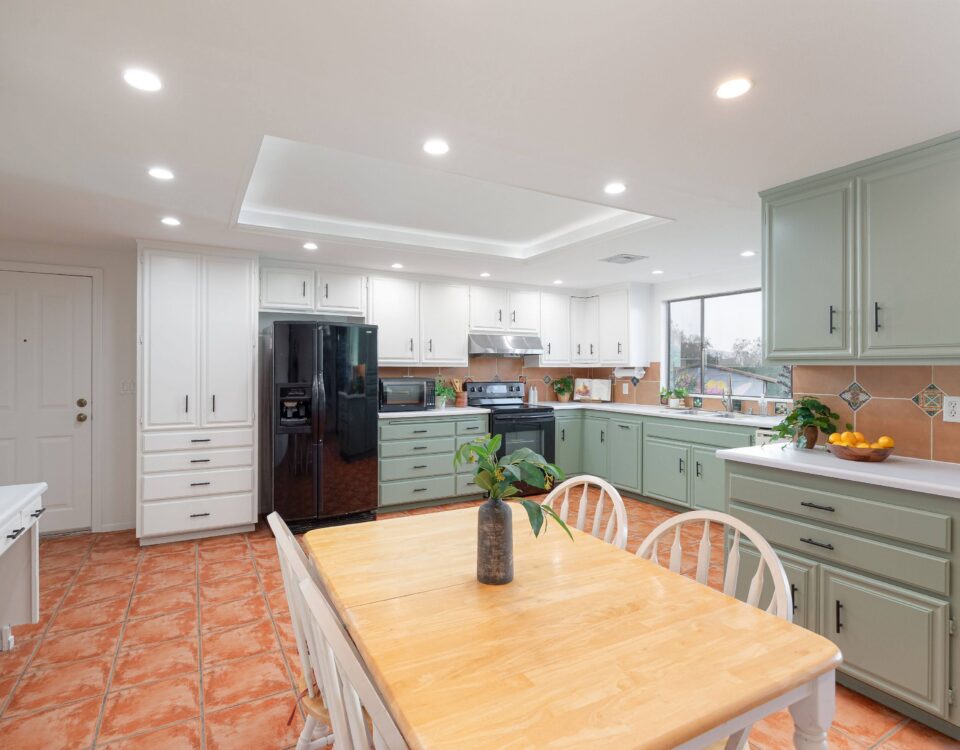 White and pale green painted kitchen cabinets with black handles in a J Brown Painting project